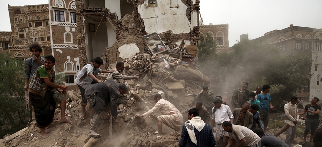2015 június 12-én a Sanaa városát ért bombázások után túlélőket keresnek a romok között; Fotó: REUTERS/Mohamed al-Sayaghi, Slate.fr