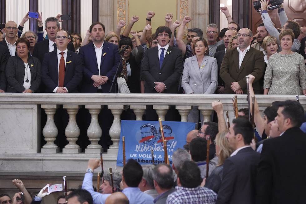 A katalán Parlament átriumában ünneplő és éneklő tömeg, a háttérben a CUP tagjai magasba tartott ököllel; kép forrása: Heraldo  