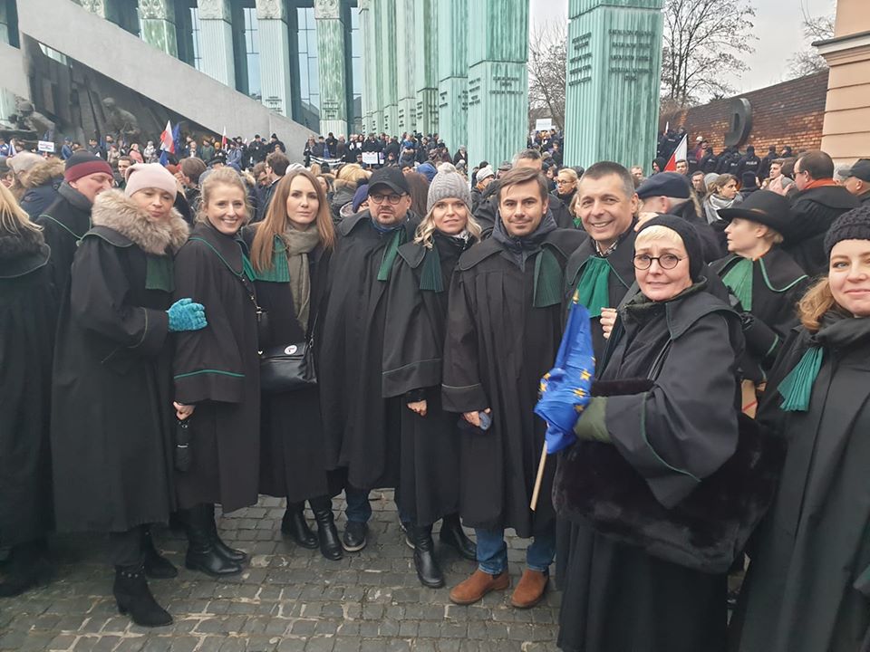 Vezető képünkön a talárba, bírói uniformisba öltözött tiltakozók egy csoportját látják a varsói Legfőbb Ügyészség épülete előtt 2020 január 11-én. Fotó: Marsz Tysiąca Tóg Facebook csoport.