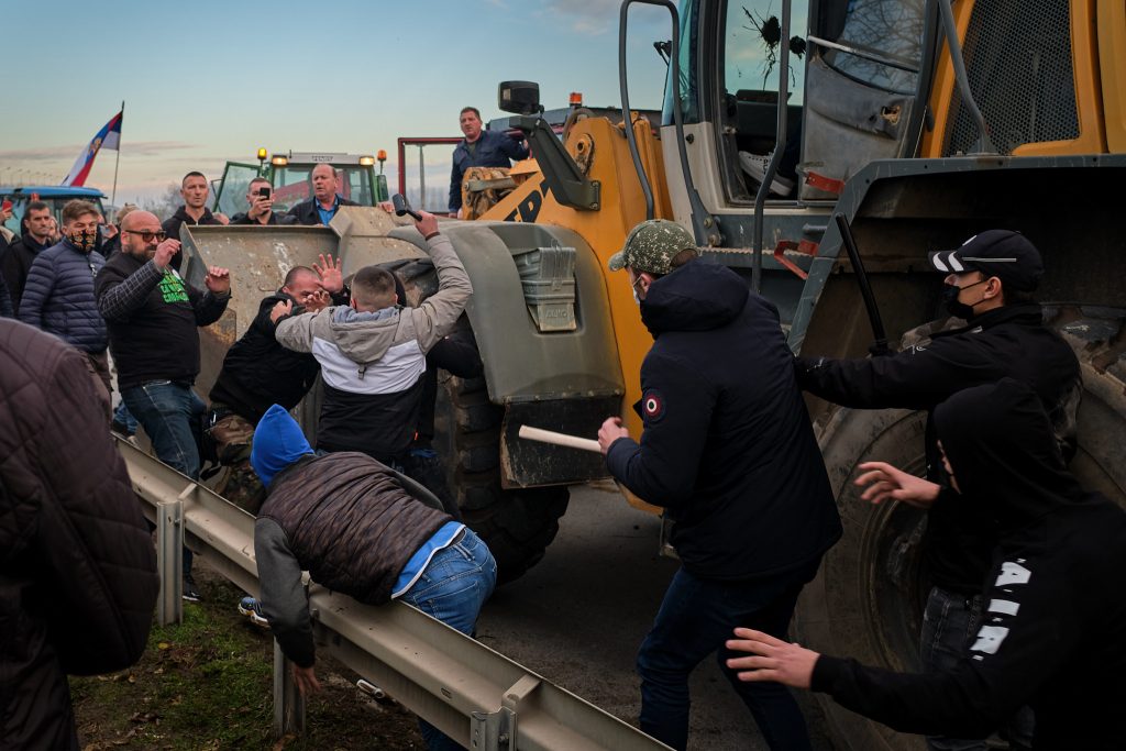 Vezető képünkön a szabácsi kalapácsembert látják akció közben 2021 november 27-én, a nyugat-szerbiai Szabács városát átszelő Száva folyó hídjánál történt összecsapás közben, amint az illiberális kormányzat helyi politikusához közel álló, arcukat eltakaró verőlegények a békés demonstrálókra támadnak. Kép forrása: Nova.rs, Fotó: Marko Zamurović