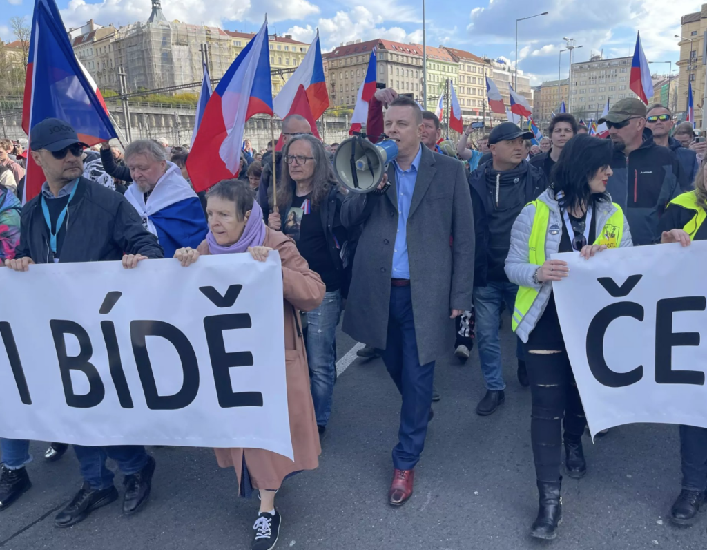 Vezető képünkön a "Csehország a nyomor ellen" elnevezésű demonstráció után a tömeg a Kormányépület elé vonult Prága belvárosán keresztül 2023. április 16-án. A menetet a cseh szélsőjobboldal új sztárja, Jindřich Rajchl vezette. Képünkön középen, mikrofonnal. Kép forrása: Twitter